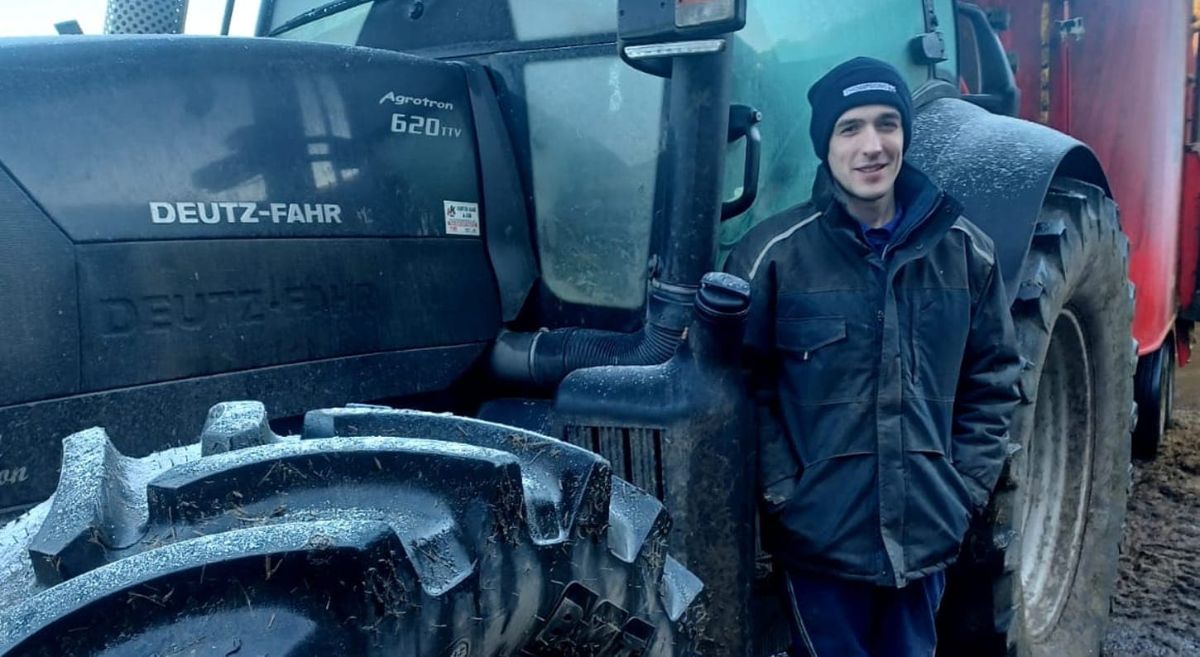 Young male pictured next to a tractor.